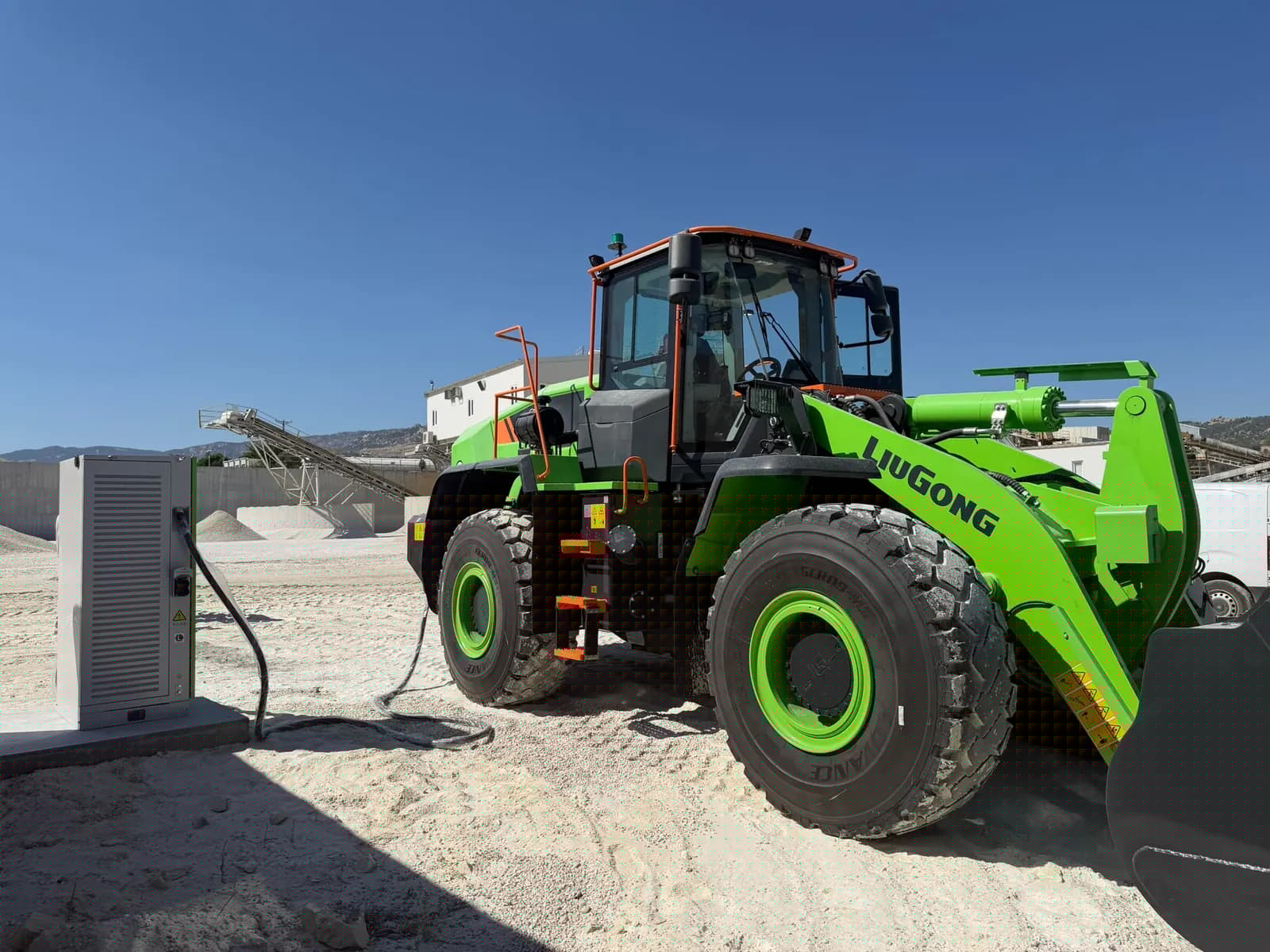 Kum ocağında beton kaide üzerindeki DC şarj ünitesi ve elektrikli yükleyici iş makinesi